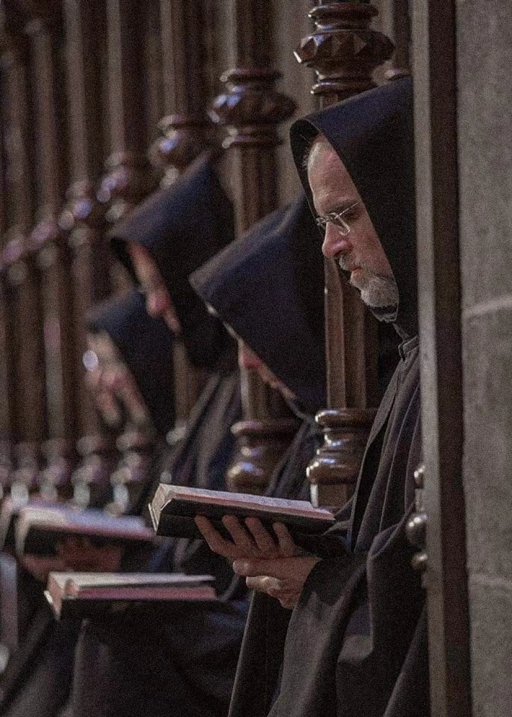 Monks standing in a row of choir stalls during the daily office.
